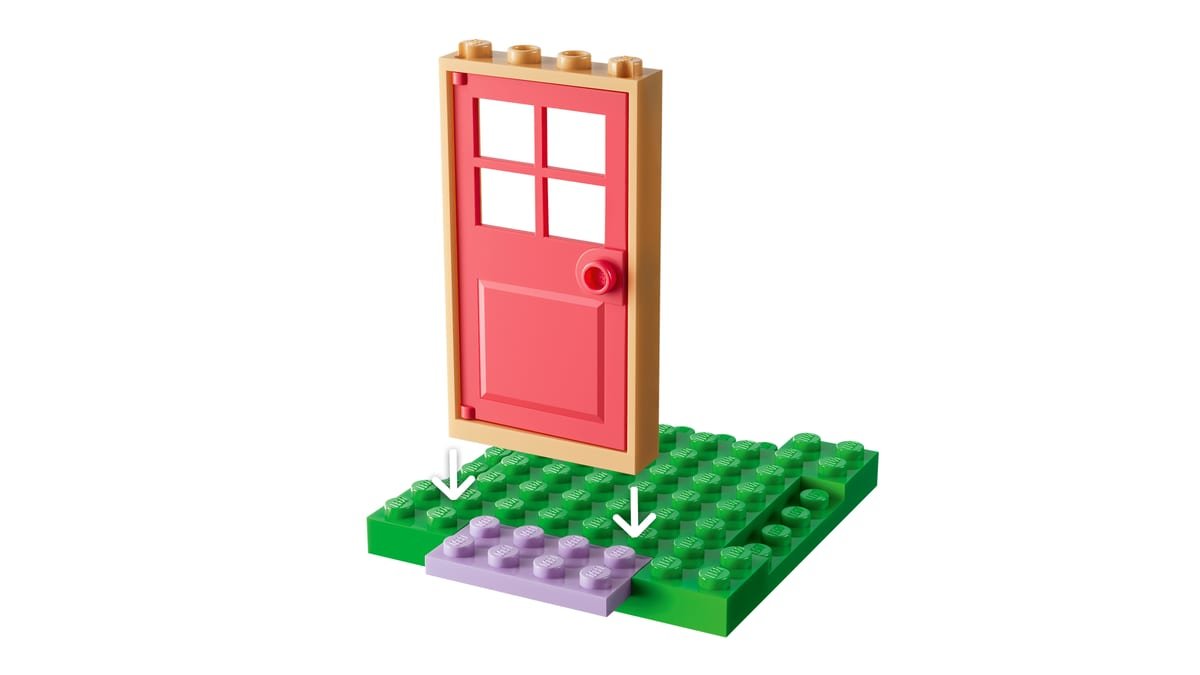 Gros plan sur la porte rose et le seuil fleuri de la maison de jardin