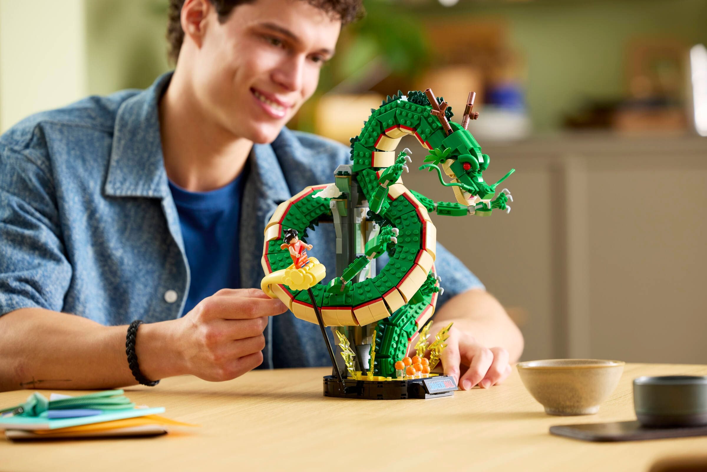 Un adulte ajuste la pose de Goku sur le modèle Shenron posé sur une table