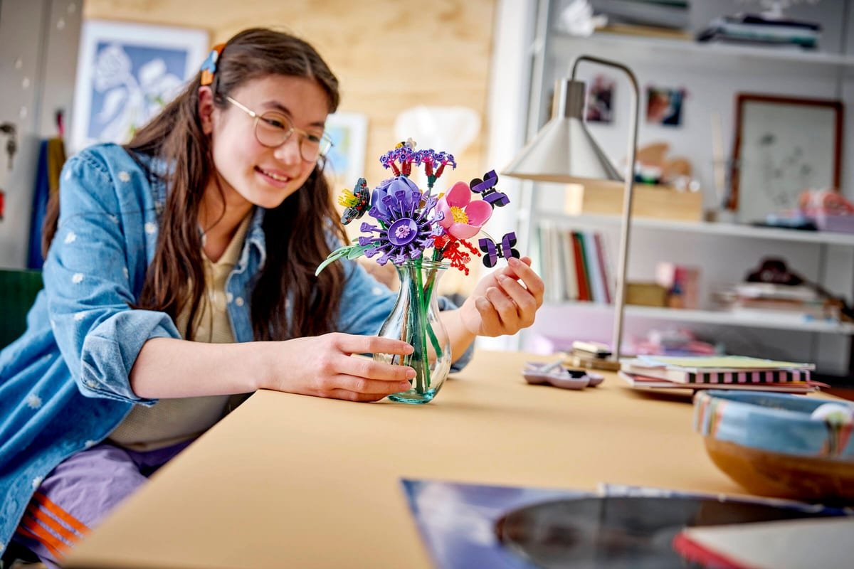 Une adolescente arrange le bouquet LEGO dans son vase sur un bureau