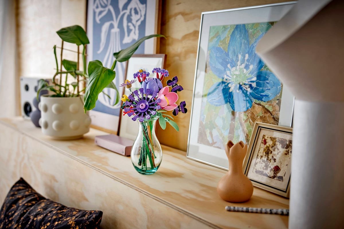 Le bouquet expose dans un vase en verre sur une etagere, entre des cadres