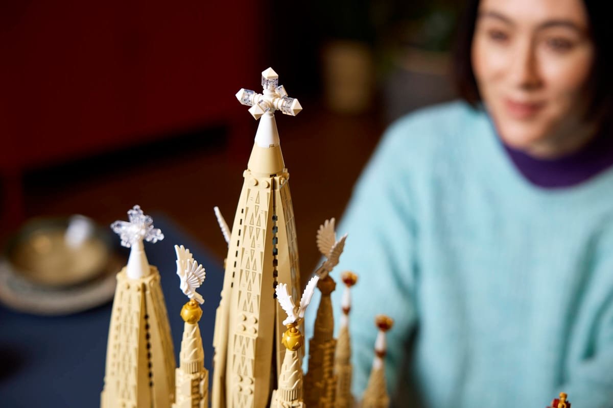 Gros plan sur le sommet de la flèche centrale du LEGO Sagrada Família, sa croix translucide et les ailes blanches des tours voisines