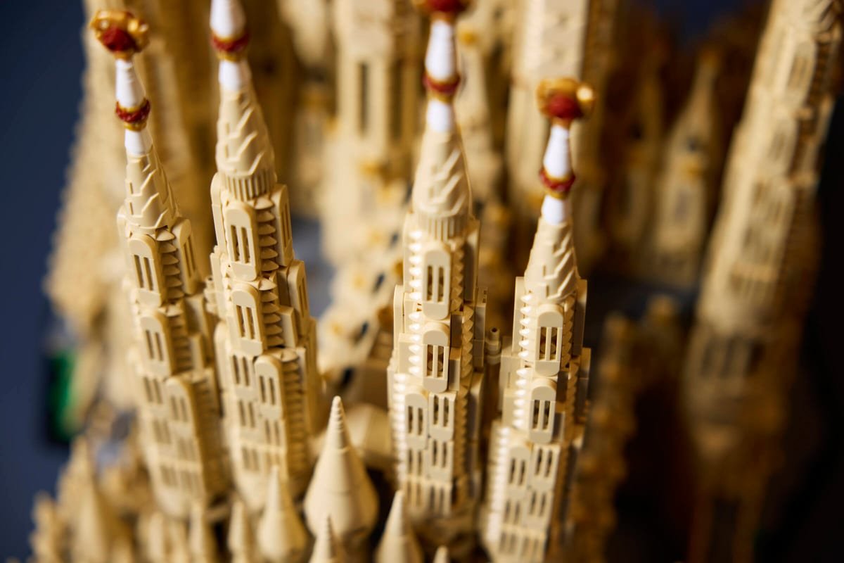 Gros plan sur plusieurs clochetons du LEGO Sagrada Família, avec leurs fûts blancs, anneaux rouges et bourgeons dorés