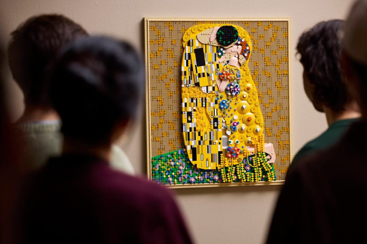 Deux personnes observent le tableau LEGO Le Baiser accroché au mur