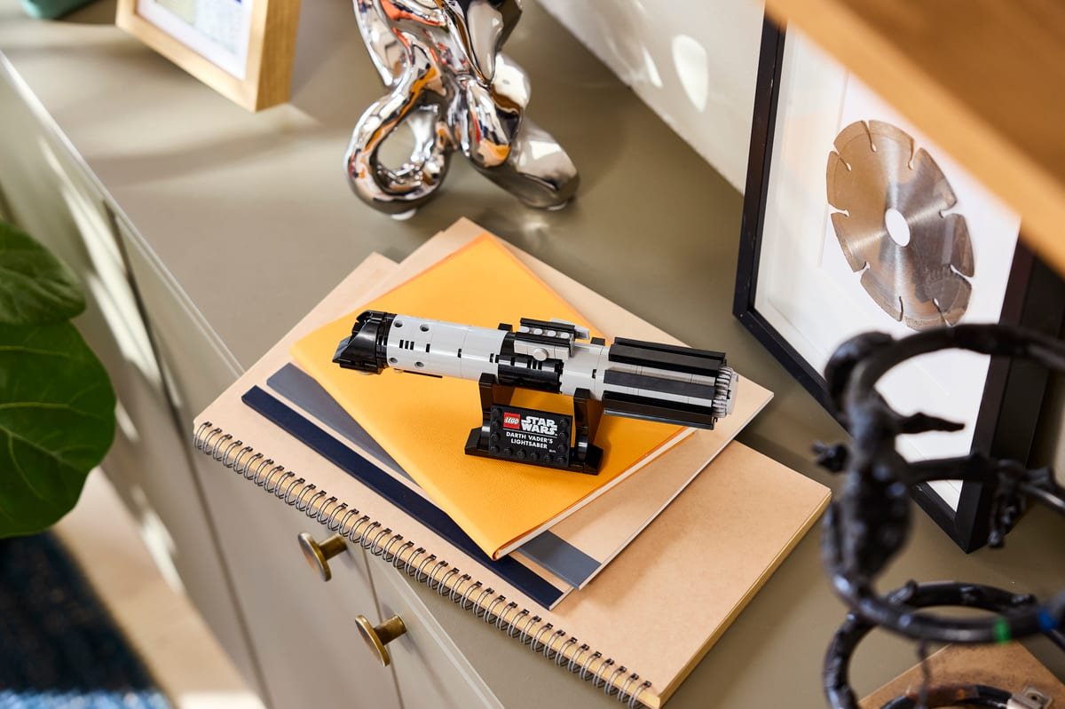 Le sabre laser LEGO posé sur une pile de carnets, dans un intérieur