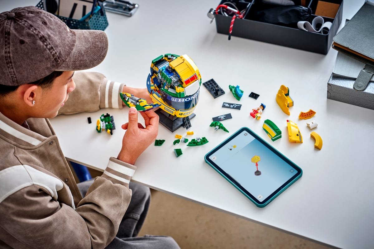 Assemblage du casque LEGO Ayrton Senna en cours sur un bureau, pièces étalées et instructions sur tablette