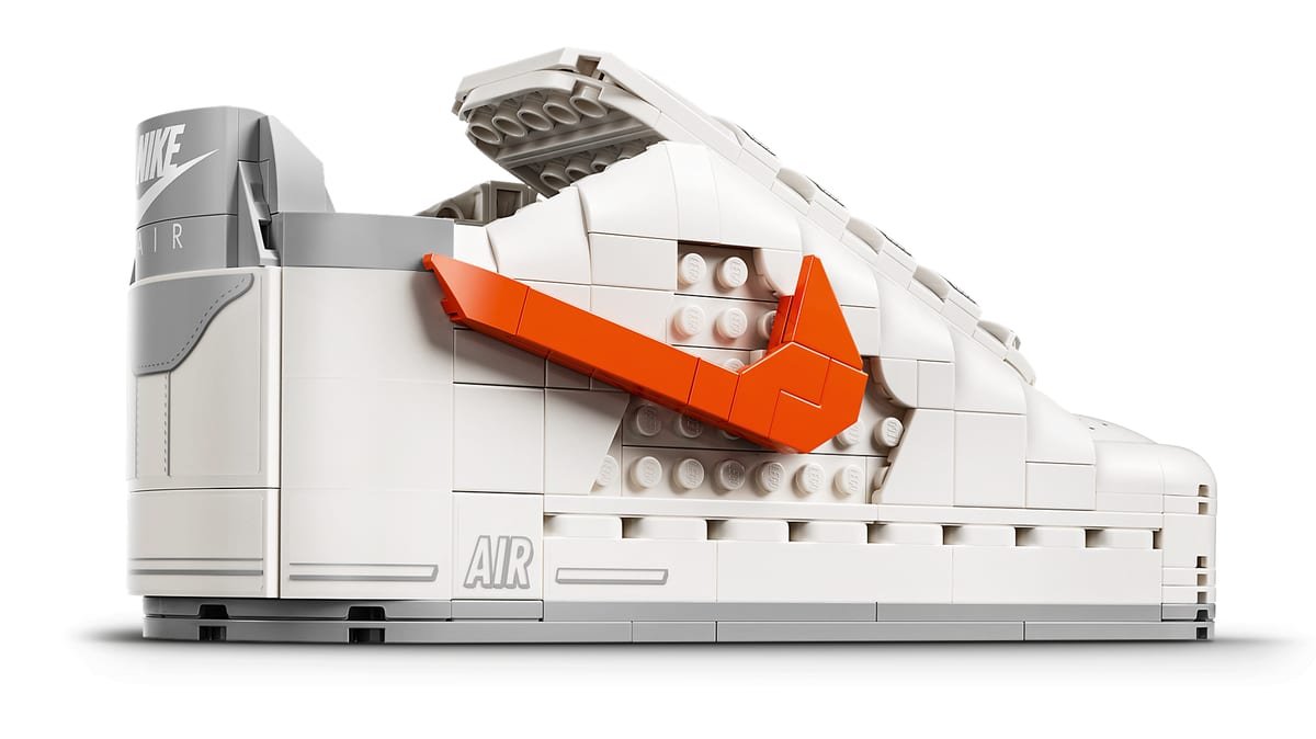 Gros plan sur la Nike Air Force 1 en briques LEGO, avec son Swoosh orange amovible et le marquage AIR sur le flanc