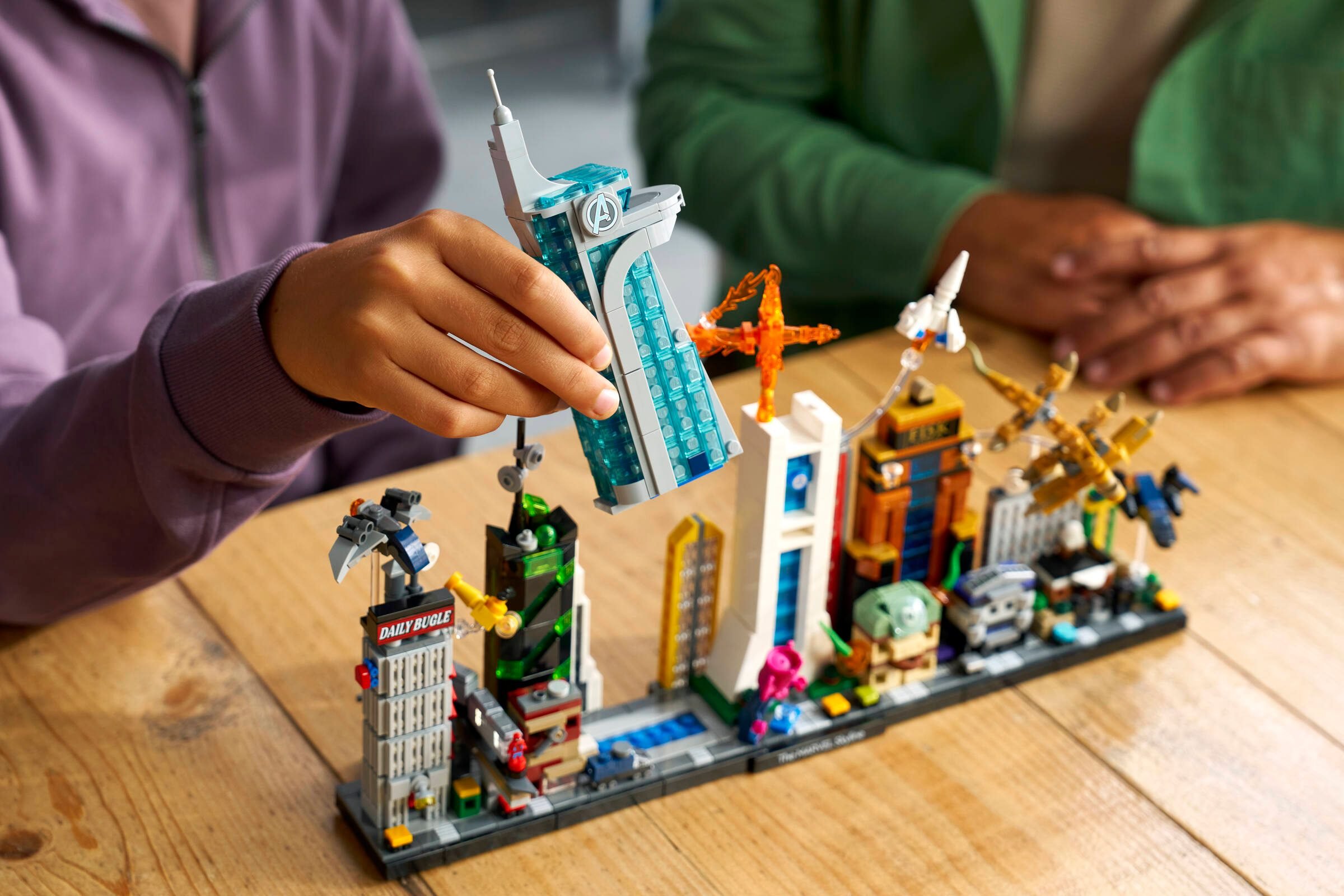 Le Panorama de Marvel monté sur une table en bois, la tour des Avengers en main