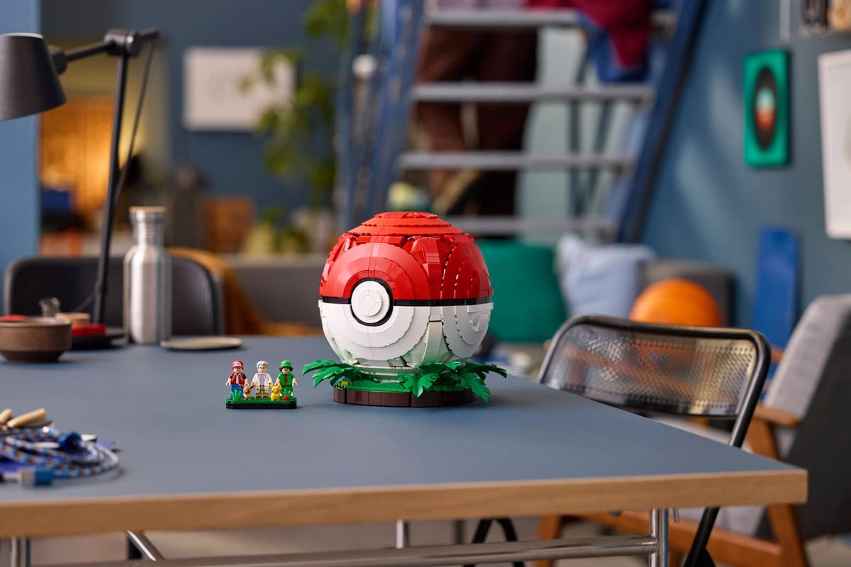 La Poke Ball fermee posee sur son socle vegetal, minifigurines a cote