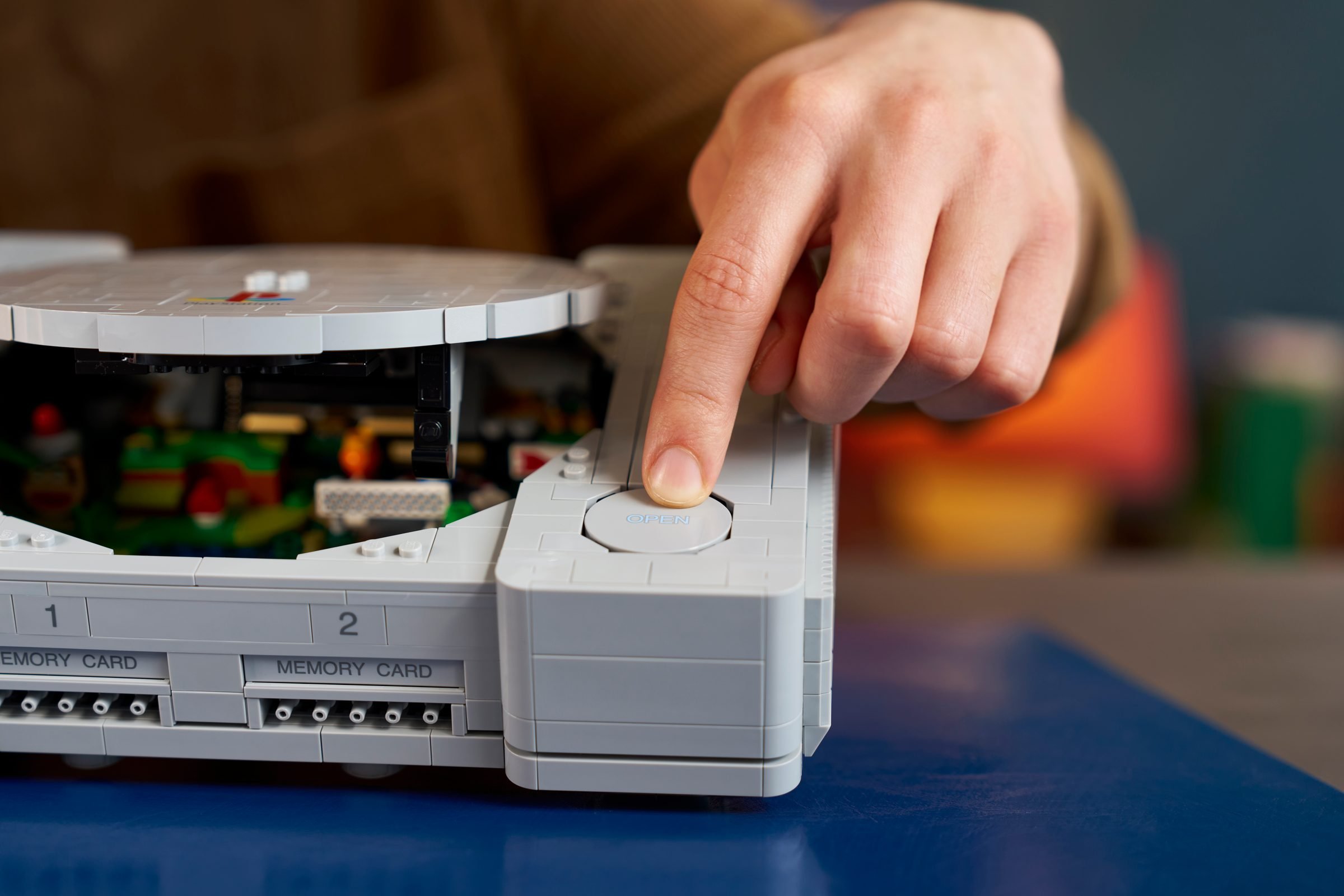 Un doigt appuie sur le bouton OPEN du LEGO PlayStation 72306