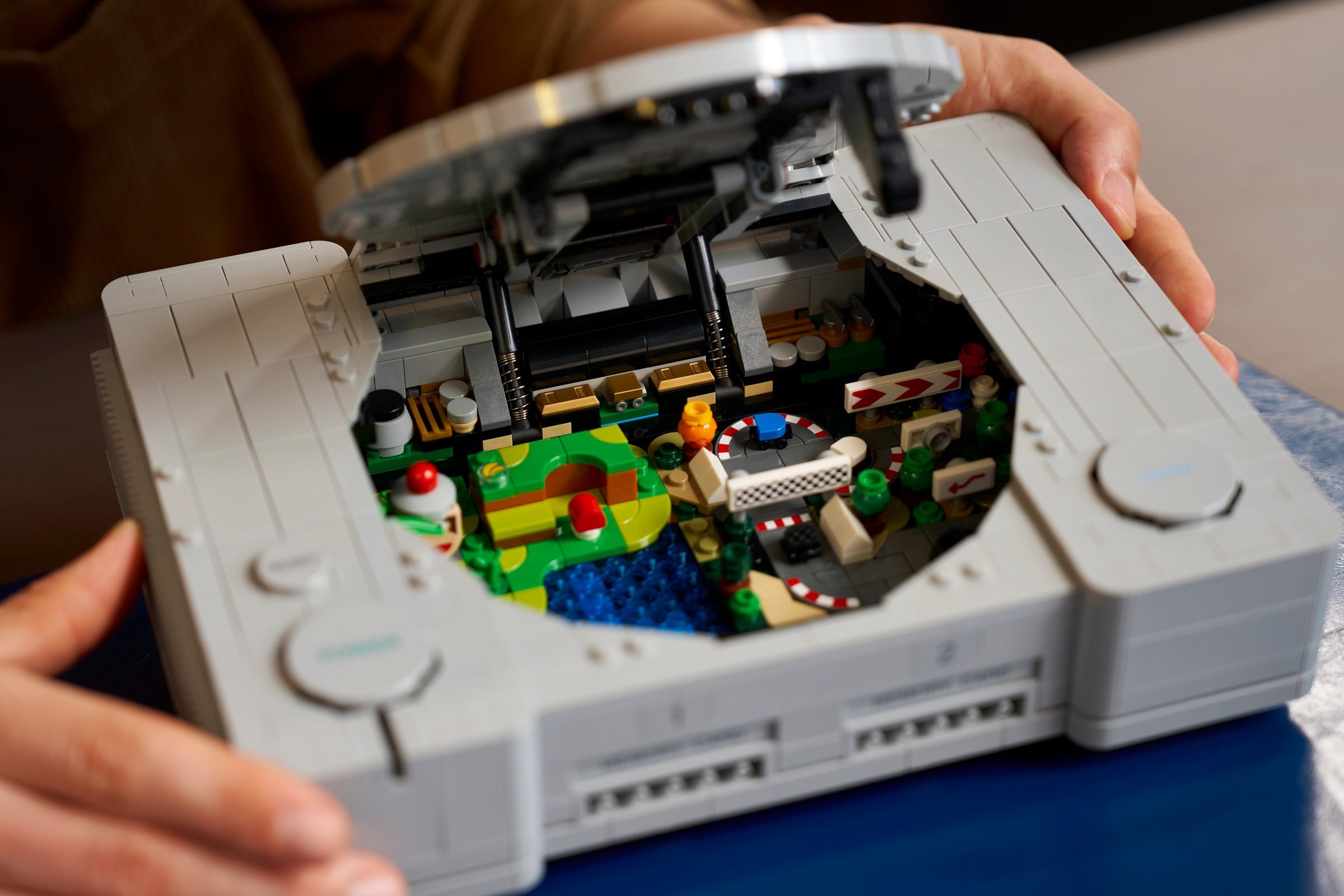 La console ouverte à deux mains, les dioramas Ape Escape et Gran Turismo visibles à l'intérieur