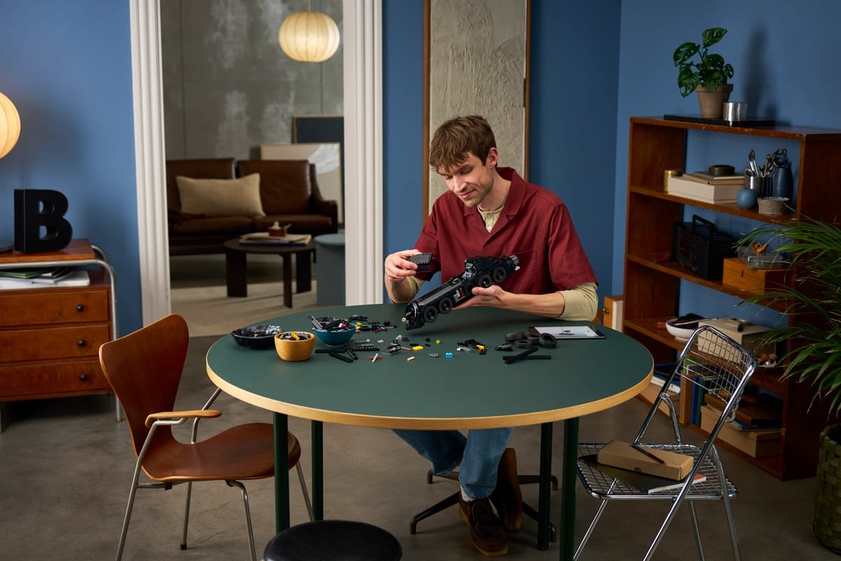 Montage du set LEGO 76355 sur une table, les pièces étalées autour du châssis de la Batmobile