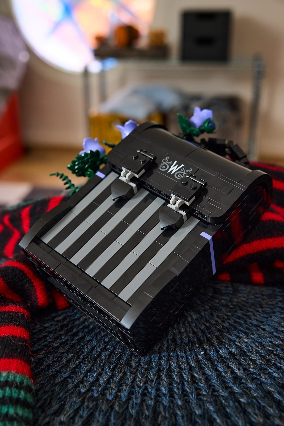 Le sac à dos de Mercredi LEGO 76787 posé sur un plaid dans une chambre
